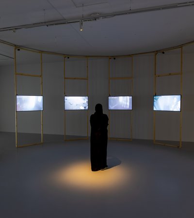 A woman standing in a room surrounded by video screens