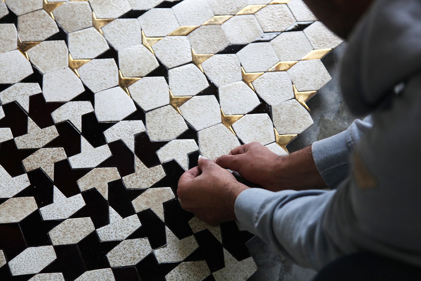 Artisan laying tiles in geometric pattern