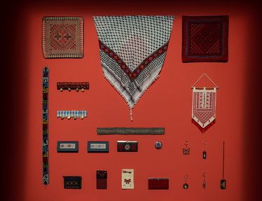 Objects with Palestinian embroidery displayed on a red wall