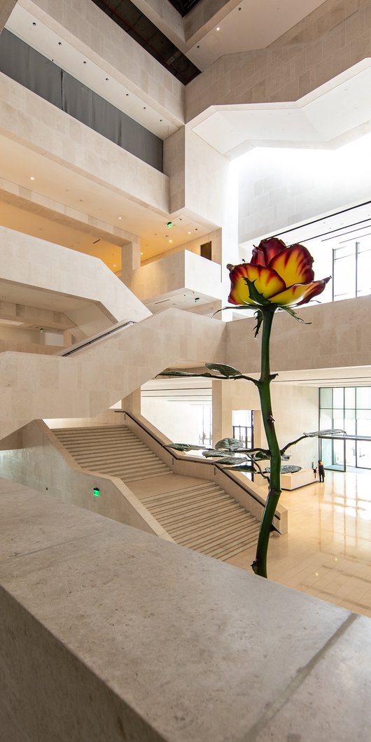 A two-story tall metal sculpture of a rose with red and white petals inside the entrance to the M7 building.