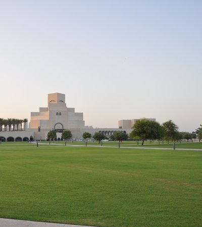 Wide angle of MIA Park, with green grass, blue sky and the museum in the background
