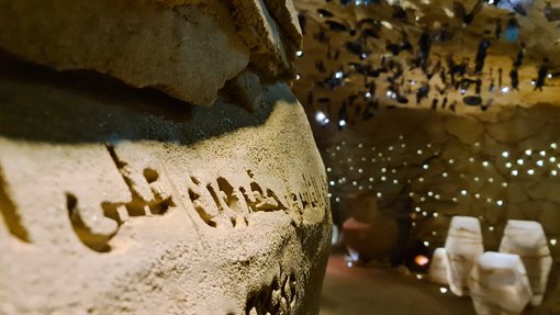 Interior of Cave of Wonders at National Museum of Qatar. There are Arabic letters carved on the cave walls with sunlight filtering through.