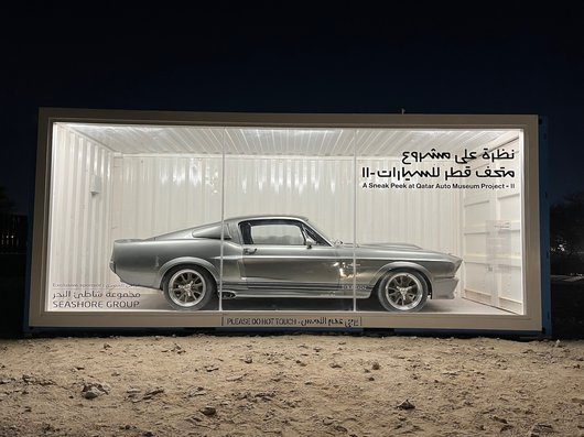 A silver 1967 Ford Mustang in a display case.