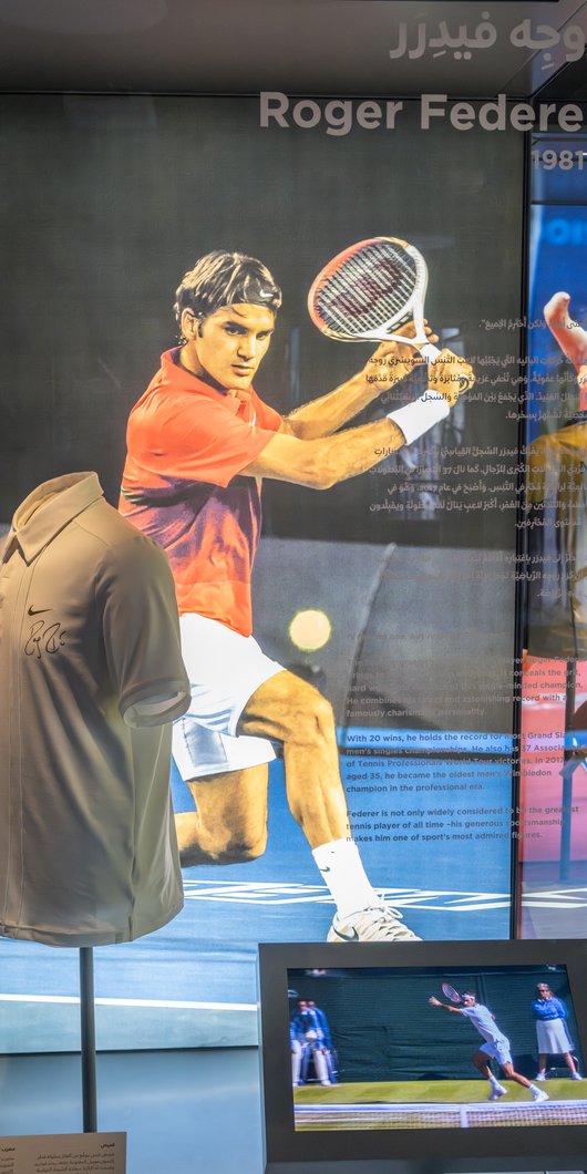 A museum gallery space that has the signed T-shirt and racquet by world-renowned tennis player Roger Federer.