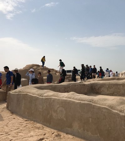 A queue of visitors walking through the clay structures of the heritage site