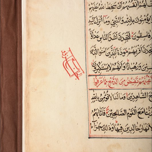 Photo showing a corner of a page from the Al Zubarah Qur'an with notes from the author in the left hand margin