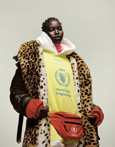 A woman with layers of clothing, including a fake fur spotted coat and yellow sweatshirt with text "World Food Programme".