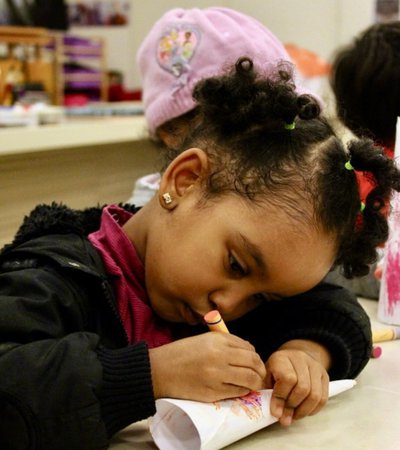 A small child focuses whilst they draw