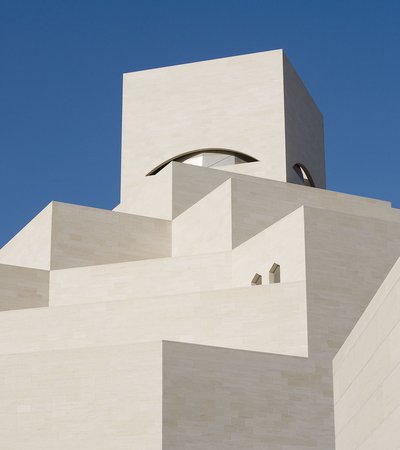 Detail of the white angular exterior of the Museum of Islamic Art with a blue cloudless sky in background