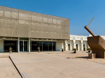 Exterior view of Mathaf entrance with large stone sculptures