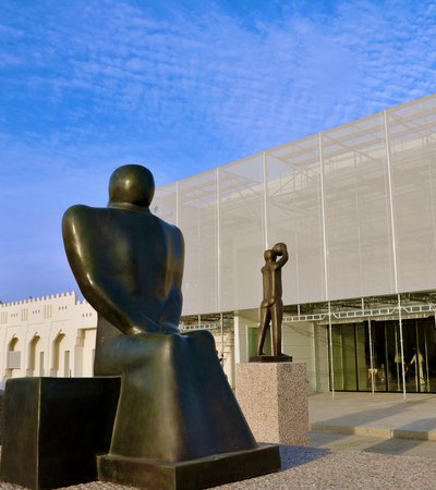 Exterior view of Mathaf: Arab Museum of Modern Art building with a group of three large sculptures positioned in front of it