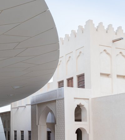 Exterior view showing the faceted shapes of the National Museum of Qatar on the left with the historic palace on the right