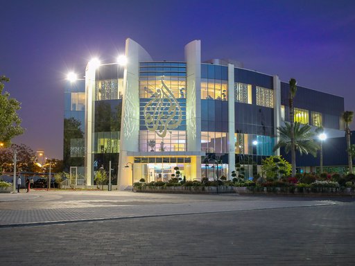 The outside of a building with the Al Jazeera logo mounted on the front.