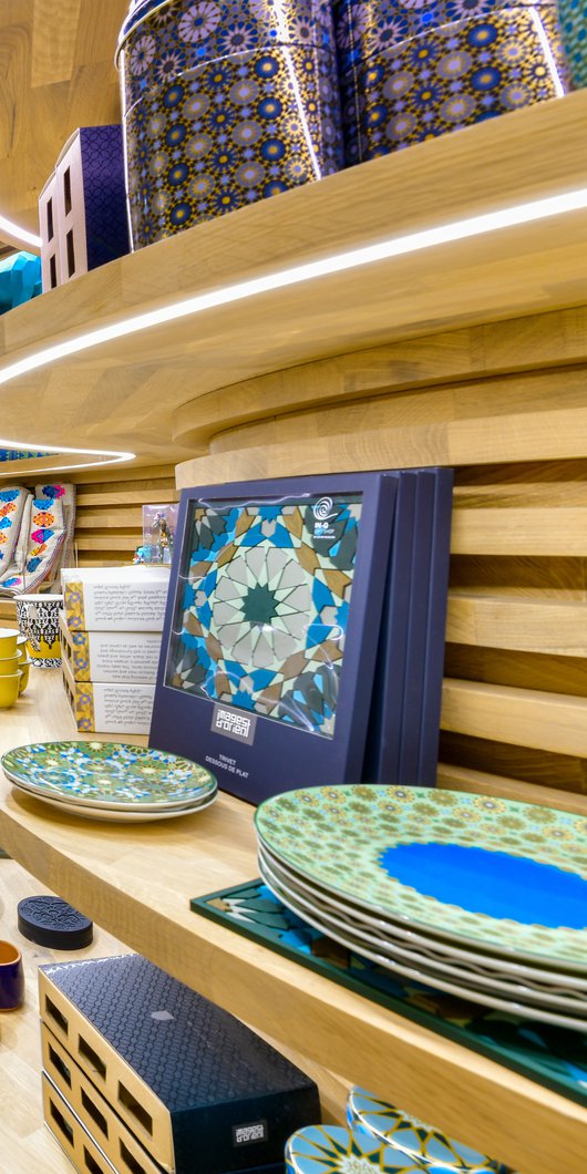 A dramatic view of the gift shop with local products displayed on curving wooden shelves at the National Museum of Qatar