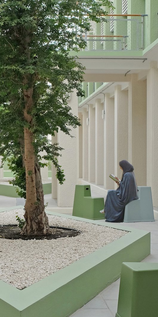 An open air courtyard, with contemporary seating and a woman reading.