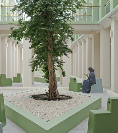 An open air courtyard, with contemporary seating and a woman reading.