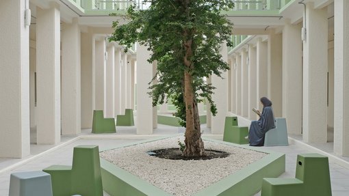 An open air courtyard, with contemporary seating and a woman reading.