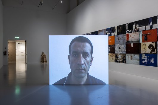 A projection of the artist, Taysir Batniji's face, in the middle of a gallery space.