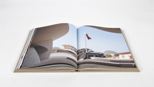 Open double page book displaying full photography of the exterior of the National Museum of Qatar