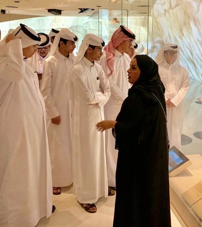 A woman tour guide explaining the National Museum of Qatar collection to students