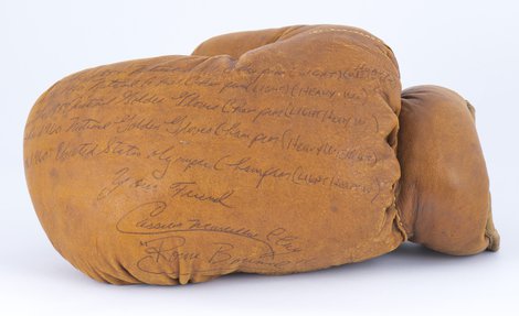 شروح مكتوبة على قفاز من الجلد بلون الكراميل، توضح بالتفصيل انتصارات الملاكمة التي نُسبت إلى محمد علي.