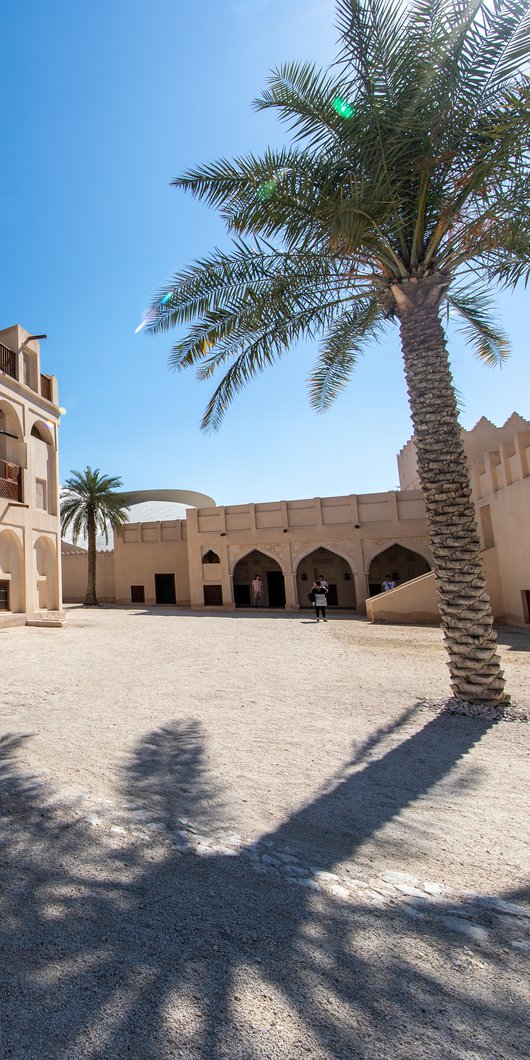 Restored historic palace with arches and sand coloured buildings in the background