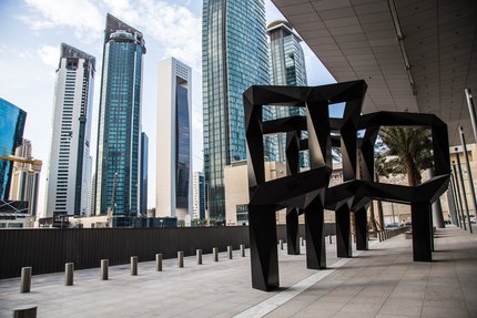 A view of Smoke, a black metal geometric sculpture by American artist Tony Smith in Doha with tall buildings in the background