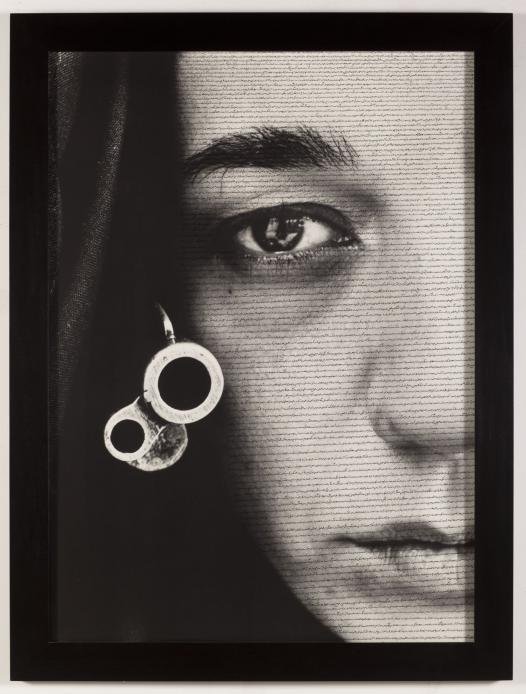 Black and white photograph depicting a frontal side portrait of an expressionless woman, while having Arabic calligraphy written on her face