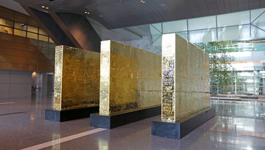 Three thick golden walls in the middle of the lobby at Hamad International Airport