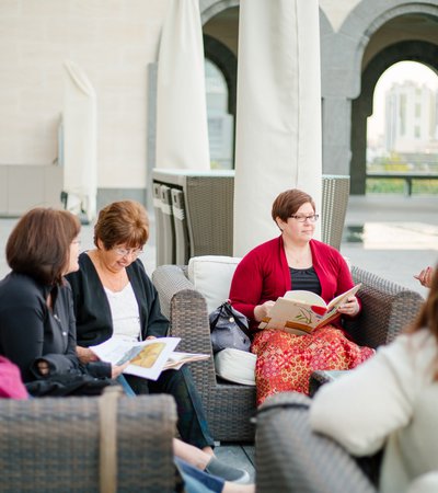 A shot of women sitting at the MIA courtyard with open books in their hands